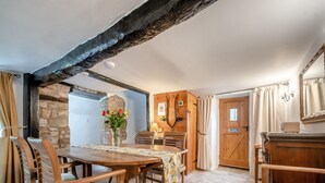 Un coin repas rustique avec une table et des chaises en bois, un mur en pierre et une poutre en bois au plafond.