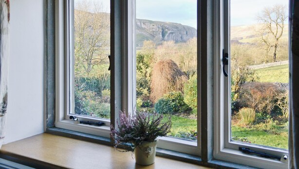 Ein Zimmer mit drei Fenstern und Blick auf eine ländliche Gegend.