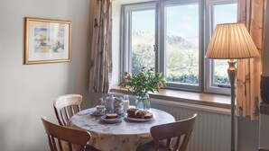 Ein Essbereich mit gedecktem Tisch für Tee, einer Blumenvase und Blick ins Freie.