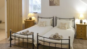 A bedroom with two beds, a wooden wardrobe, bedside tables with lamps, and a window with blinds. - 4 bedroom accommodation in Longhirst, near Morpeth (Longhirst, near Morpeth)