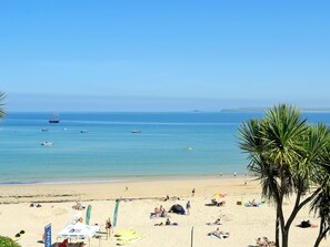 Une plage avec des kayaks, une tente pour les surfeurs et des gens qui se détendent.