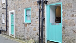 A stone building with turquoise doors and windows, a visible sign reading 'DRIFTWOOD,' and a small step leading to the entrance. - 1 bedroom accommodation in St Ives (St Ives)