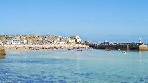 A coastal town with a sandy beach, a lighthouse, and a row of buildings along the shore. - 1 bedroom accommodation in St Ives (St Ives)