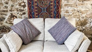 A two-seater sofa with two cushions against a stone wall backdrop. - 1 bedroom accommodation in St Ives (St Ives)