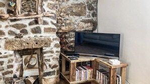 A stone fireplace with a television on a wooden stand, surrounded by bookshelves. - 1 bedroom accommodation in St Ives (St Ives)