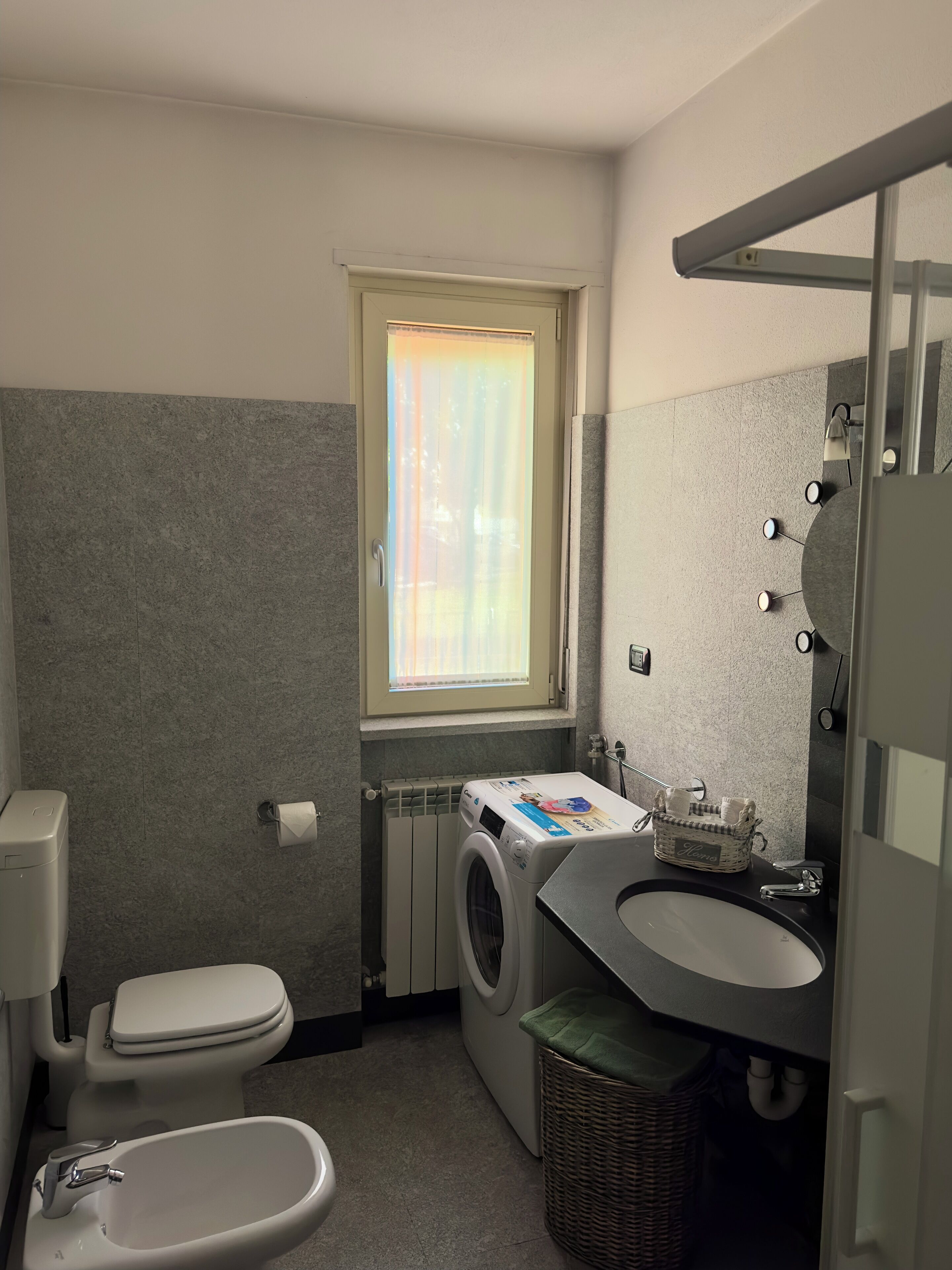 Un bagno compatto con servizi igienici, bidet, lavatrice e lavandino.
