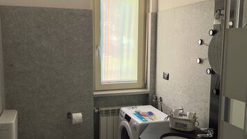 Un bagno compatto con servizi igienici, bidet, lavatrice e lavandino.