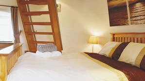 Una cama bien hecha con cabecera de madera, una lámpara de noche y una toalla en el suelo.
