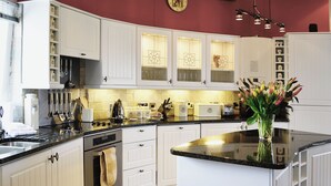 Una cocina con gabinetes blancos, una estufa y un fregadero. Hay un florero con flores en la encimera.