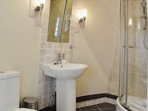 Une salle de bain avec un lavabo blanc, une douche en verre et un mur carrelé.