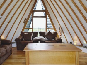 A cozy loft bedroom with a wooden sloped ceiling, a large window, a wooden bed, and a small table. - 2 bedroom accommodation in Tynlon, near Rhosneigr (Tynlon, near Rhosneigr)