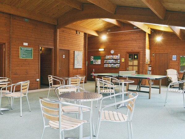 A wooden cabin with a ping pong table, chairs, and a map on the wall.