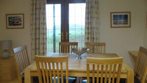 A dining area with a wooden table and chairs, a metal bowl, and two framed pictures on the walls. - 3 bedroom accommodation in Turriff (Turriff)
