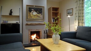 A living room with a fireplace, a sofa, a coffee table, and a bookshelf. - 3 bedroom accommodation in Turriff (Turriff)