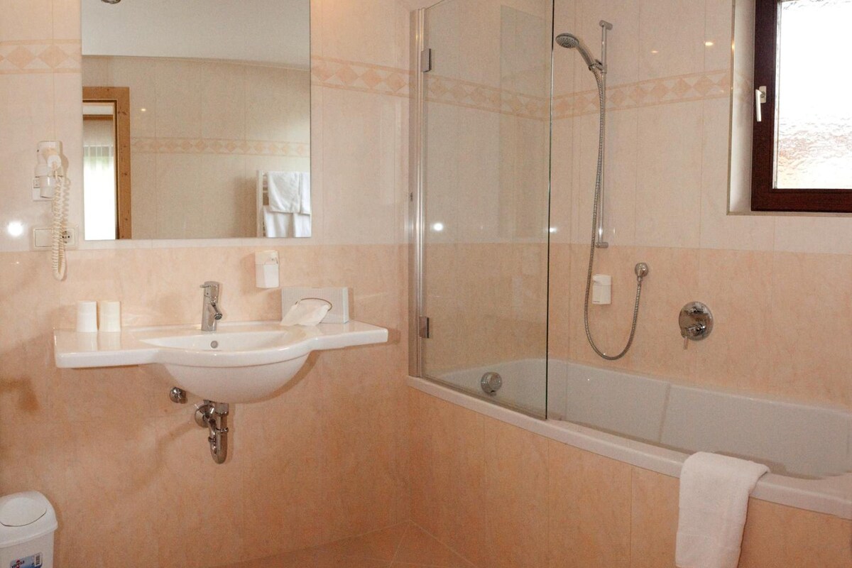 A bathroom with a glass-enclosed shower, a sink, and a bathtub.