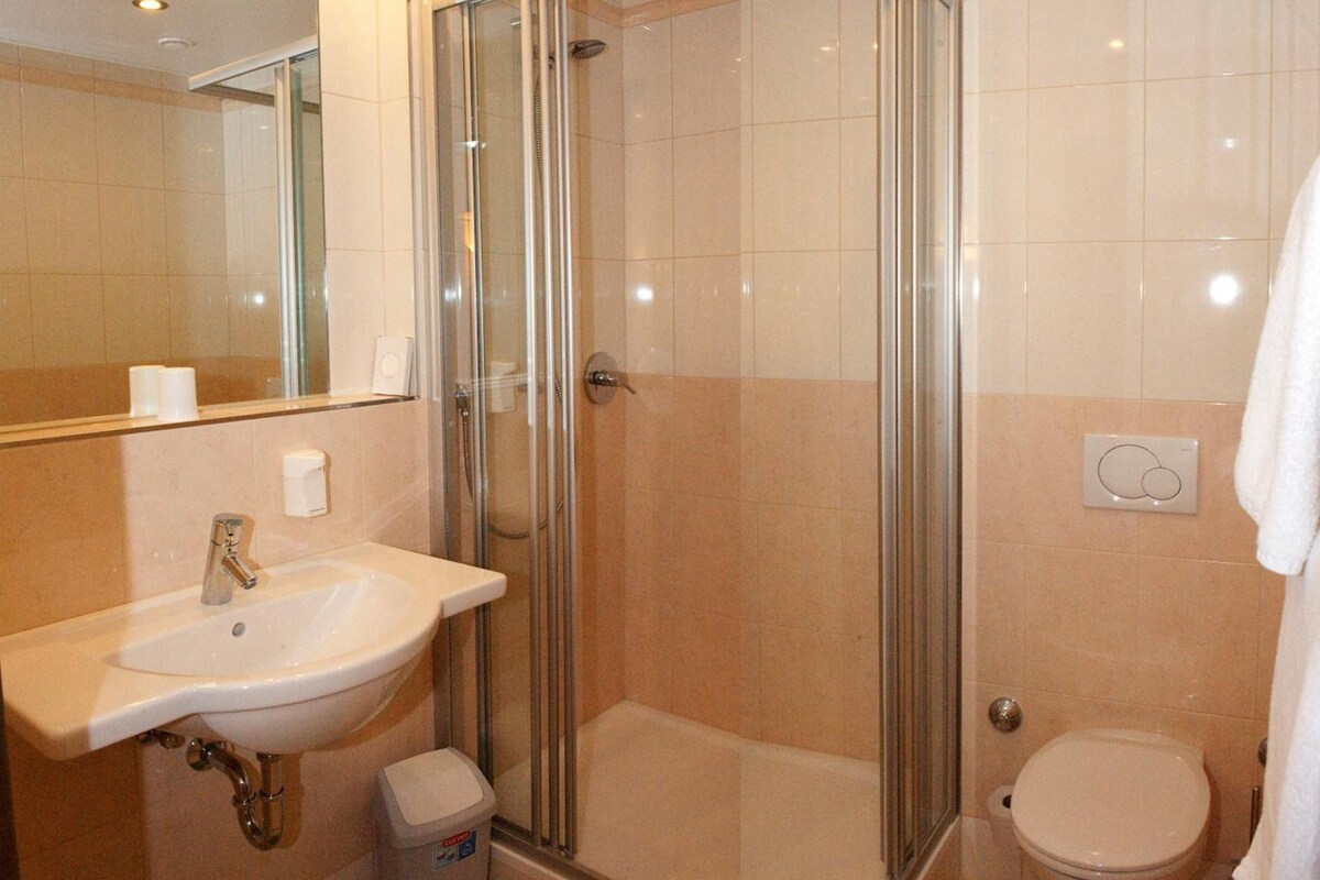 Un baño con cabina de ducha de vidrio, un lavamanos y un inodoro.