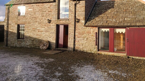 A two-story stone building with a sloped roof, a wooden door, and a window. - 3 bedroom accommodation in John O’ Groats (John O’ Groats)