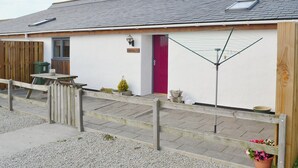 A single-story building with a red door, a small window, and a clothesline. - 2 bedroom accommodation in Towan Cross, near Porthowan (Towan Cross, near Porthowan)