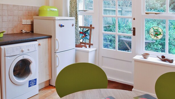 Cocina compacta con lavadora, un refrigerador pequeño y ventana con vistas a zonas verdes.