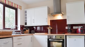 Una cocina moderna con armarios blancos, una campana extractora de acero inoxidable y un lavavajillas.
