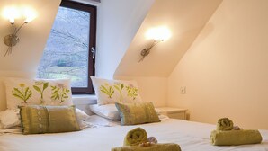 Un dormitorio con una cama grande, dos mesitas de noche y una ventana con vistas a árboles desnudos.