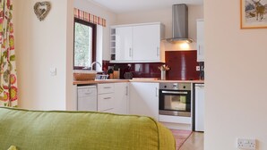 Una cocina moderna con armarios blancos, una campana extractora de acero inoxidable y una ventana con cortinas.