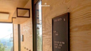 A hallway with a wooden wall and a sign with text in German. - BERGHEIM Container Lofts, Holidays directly in the Ski & Bikewelt, Container "Drop" (Schöneck/Vogtland)