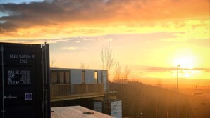 A shipping container with weight and capacity details, a wooden deck, and a building with a balcony under a sunset sky. - BERGHEIM Container Lofts, Holidays directly in the Ski & Bikewelt, Container "Drop" (Schöneck/Vogtland)