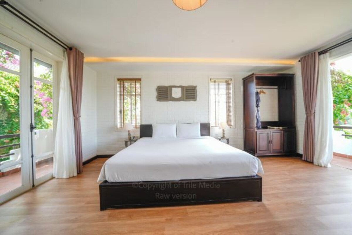 A bedroom with a large bed, a wardrobe, and a bathroom visible through an open door.