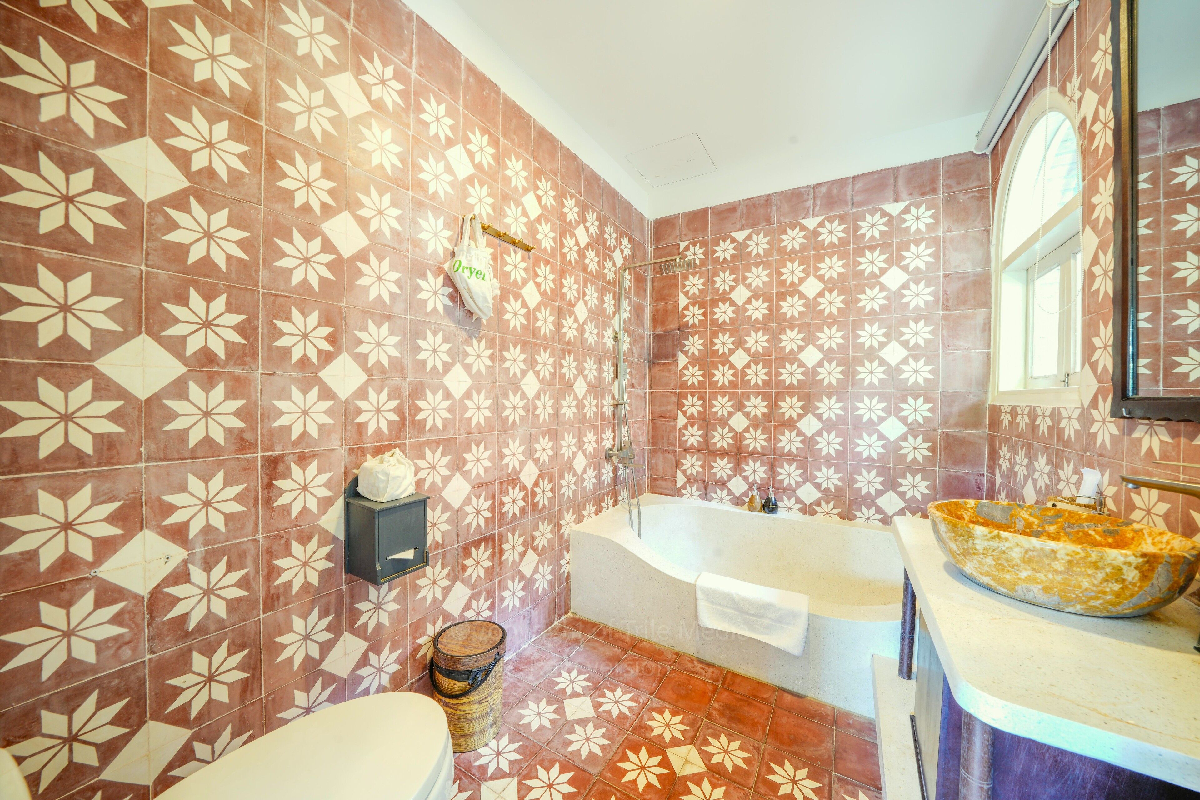 A bathroom with patterned tiles, a bathtub, a sink with a bowl basin, and a toilet.