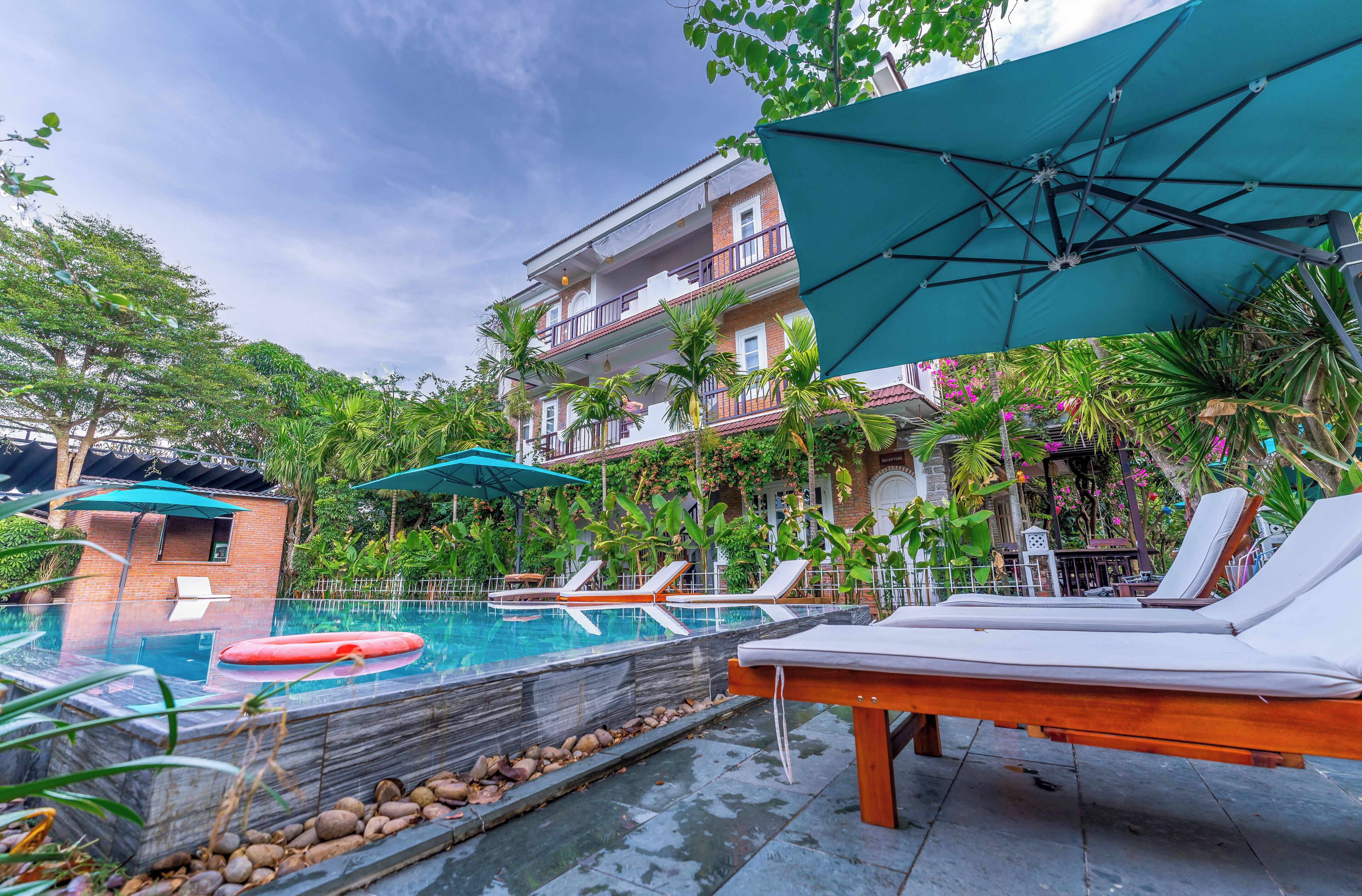 A pool area with lounge chairs, umbrellas, and a wooden deck.