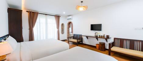 Habitación de hotel con dos camas, un escritorio con silla, un televisor y un banco.