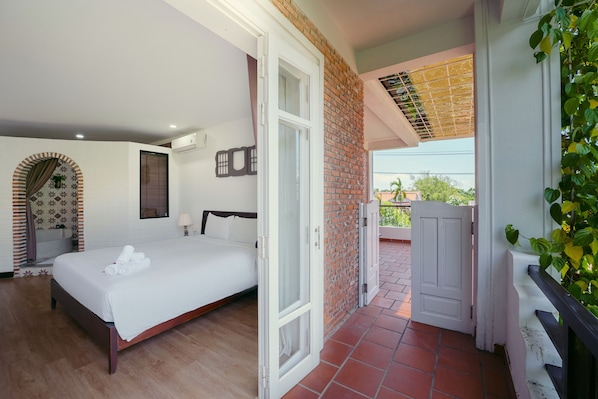 A hotel room with a bed, a door leading to a balcony, and a view of the outside.