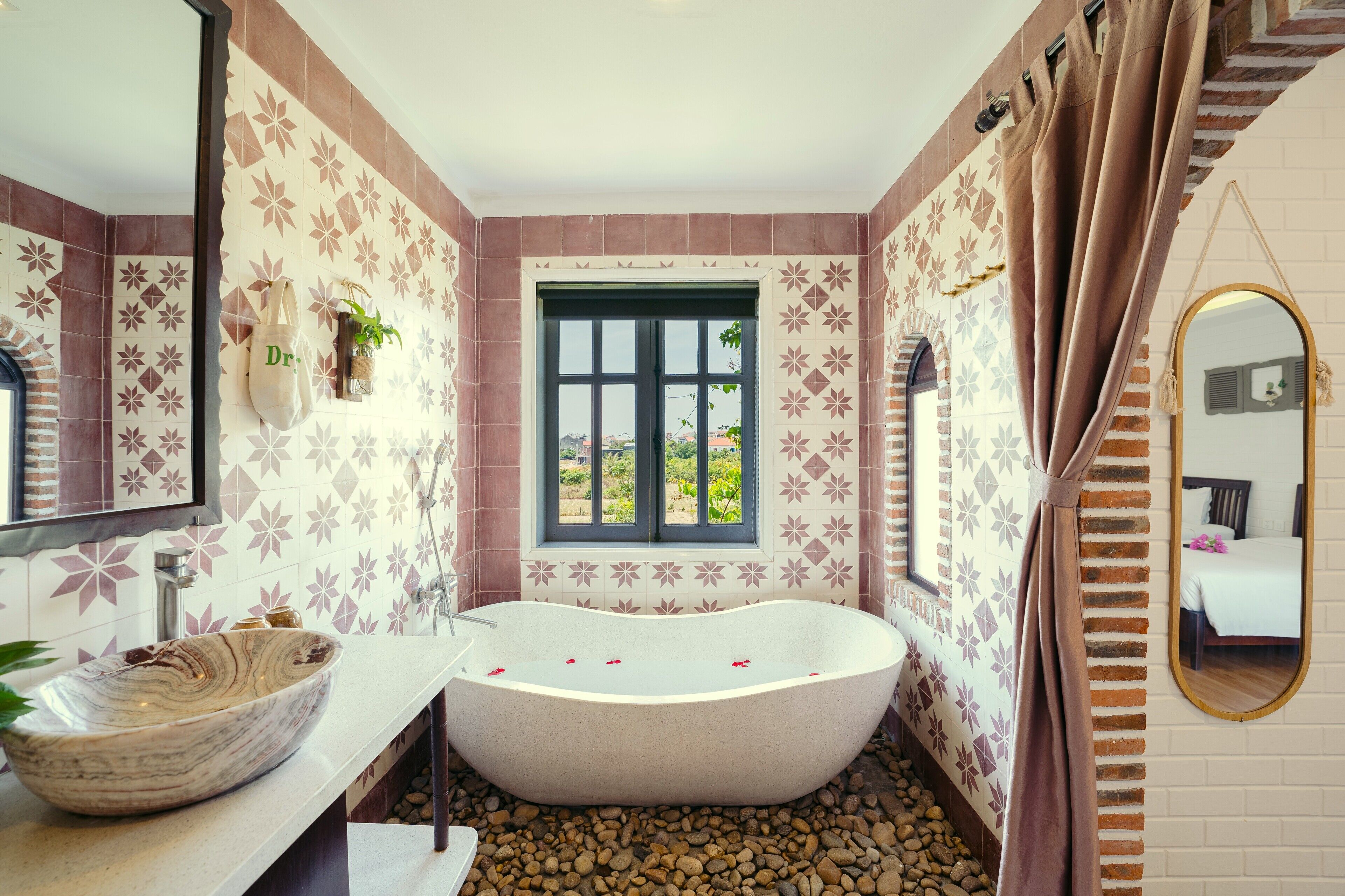 A bathroom with a freestanding bathtub, a sink, and a window with a view of greenery.