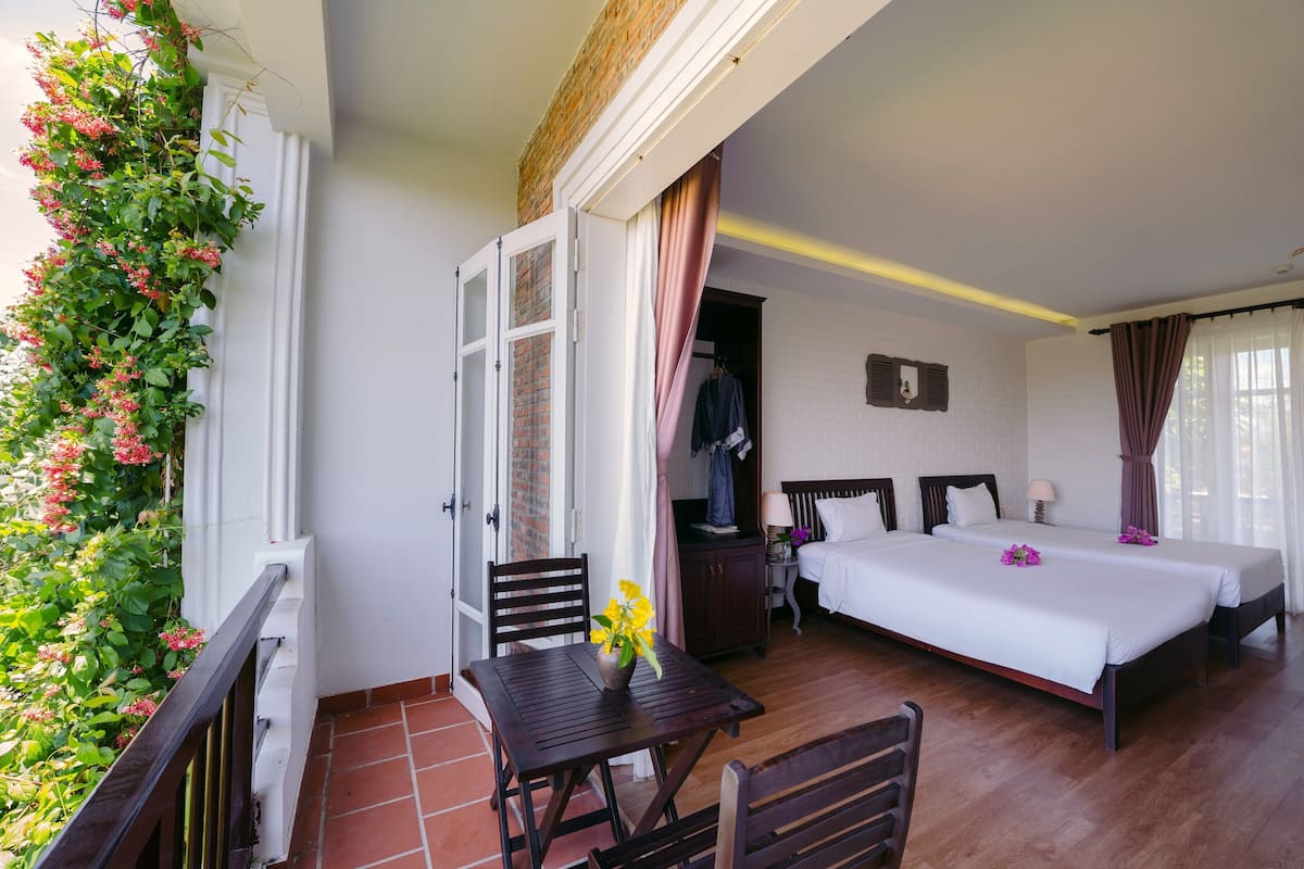 A hotel room with a balcony, a bed, a desk, and a chair.