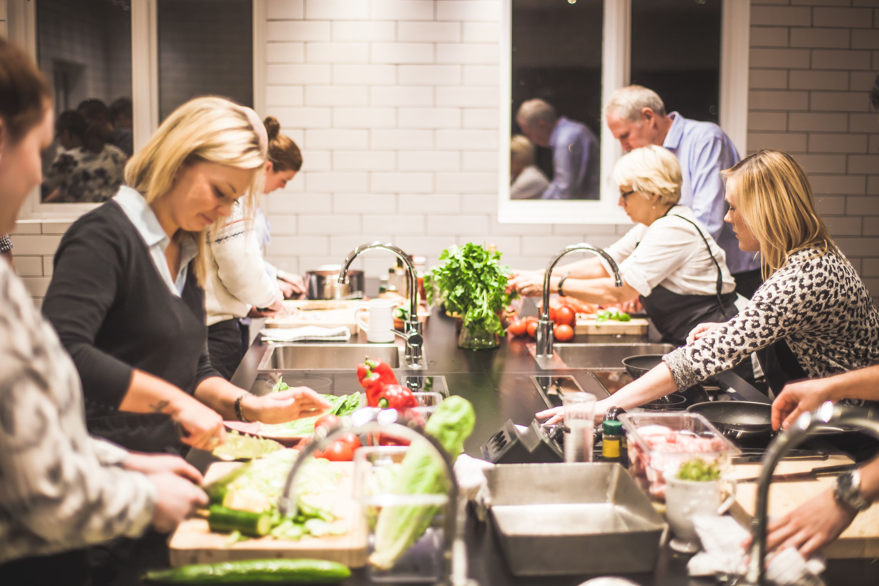A communal kitchen area with multiple people preparing food.