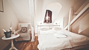 A cozy bedroom with a bed, a chair, and a small table with a champagne bucket. - Ulvhälls Herrgård (Strängnäs)
