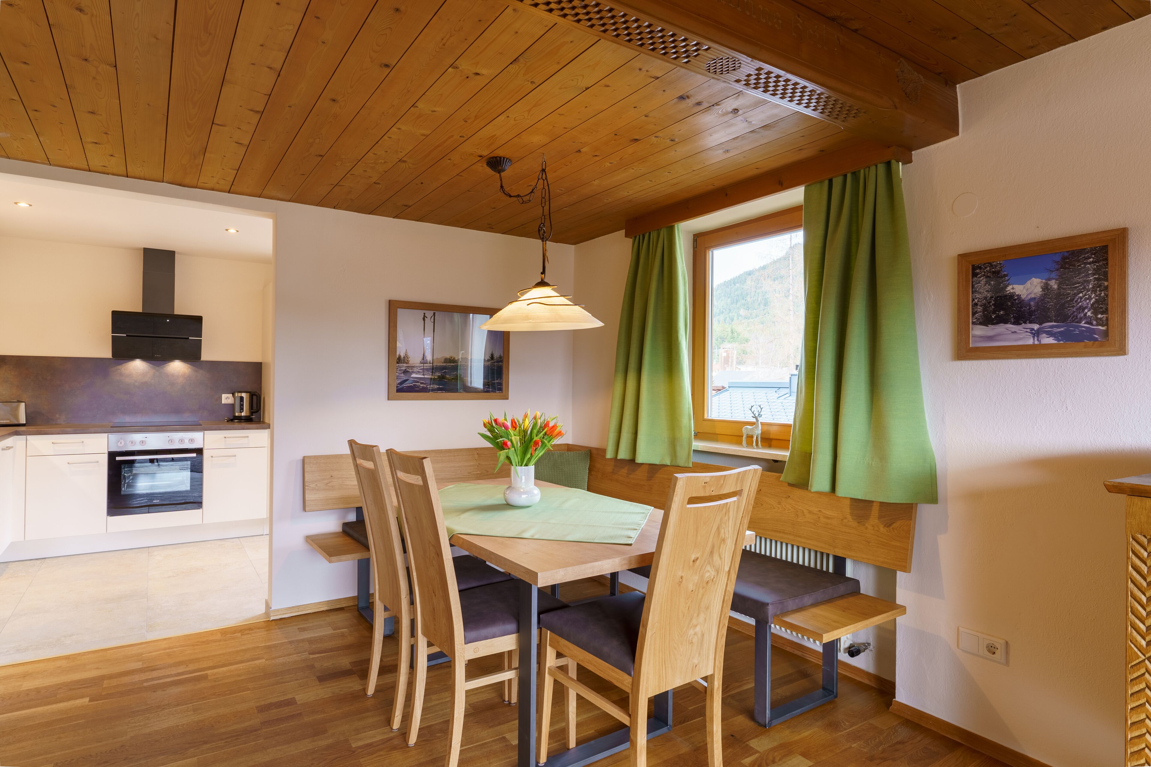 A modern kitchen with wooden cabinets, a built-in oven, and a dining area with a wooden table and chairs.