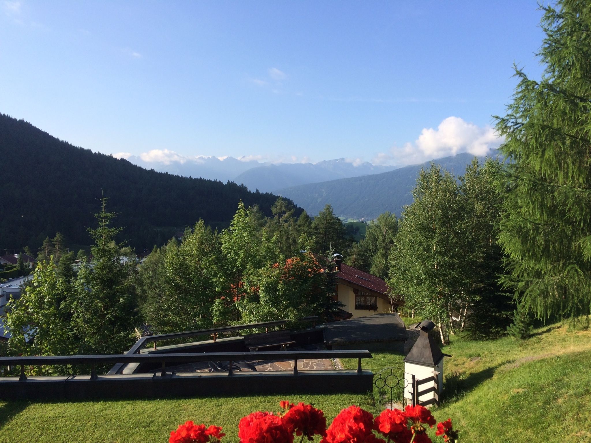 Una vista panorámica de un paisaje montañoso con una casa y un área de picnic en primer plano.