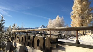A sign with the name "WAGDHOF" on a bridge with snow-covered trees and mountains in the background. - Apartmenthaus Jagdhof (Reith bei Seefeld)