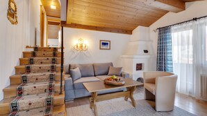 A living room with a staircase, a sofa, a coffee table, and a chair. - Apartmenthaus Jagdhof (Reith bei Seefeld)