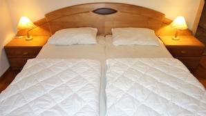 Ein Doppelbett mit Holz-Kopfteil, zwei Nachttische mit Lampen und ein kleines Fenster darüber.