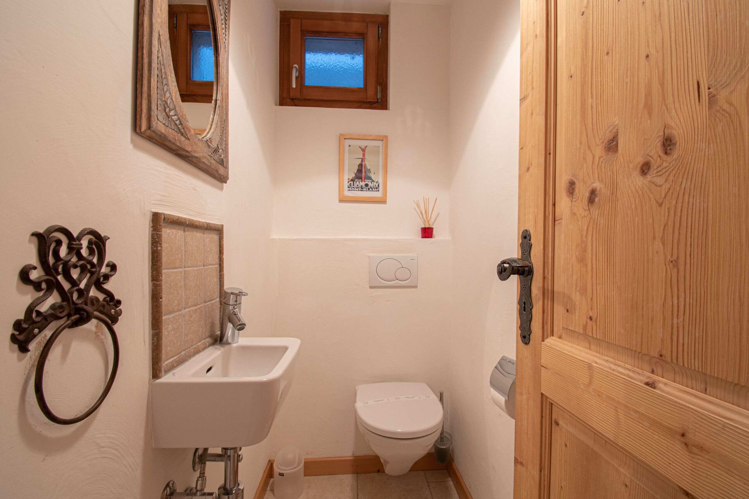 Ein kleines Badezimmer mit Waschbecken, Toilette und einer Holztür.