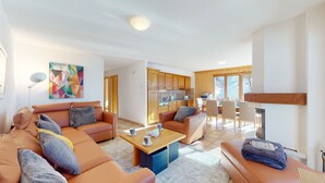 Ein modernes Wohnzimmer mit einer Sofagarnitur, einem Couchtisch und einem Essbereich mit Stühlen.