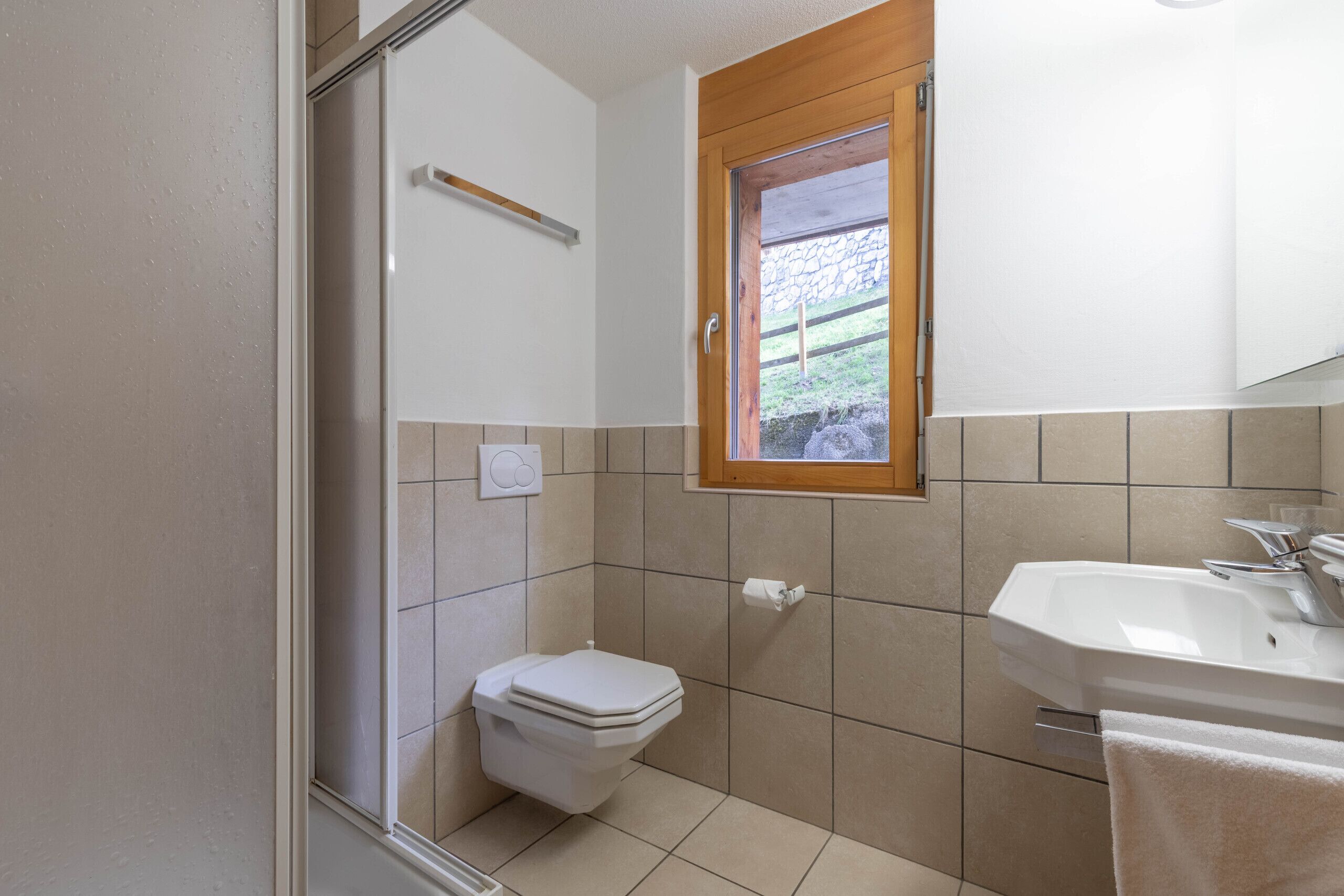A bathroom with a toilet, sink, and window.