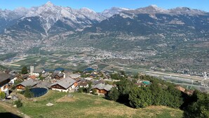 Un pueblo de montaña con edificios residenciales y comerciales, una iglesia destacada y vistas de las montañas circundantes.