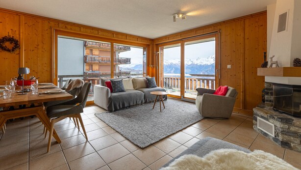 Un amplio salón con detalles de madera, una chimenea y un balcón con vistas a la montaña.