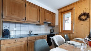 Una cocina con armarios de madera, encimera de granito y comedor para cuatro.