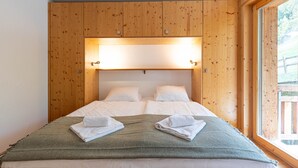 Una cama doble con cabecera de madera, dos almohadas blancas y una manta verde.
