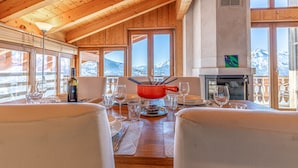 A wooden interior with a dining area, large windows, and a fireplace. - Balcons du Soleil Y2 221 - QUIET apartment 8 pers (Veysonnaz)
